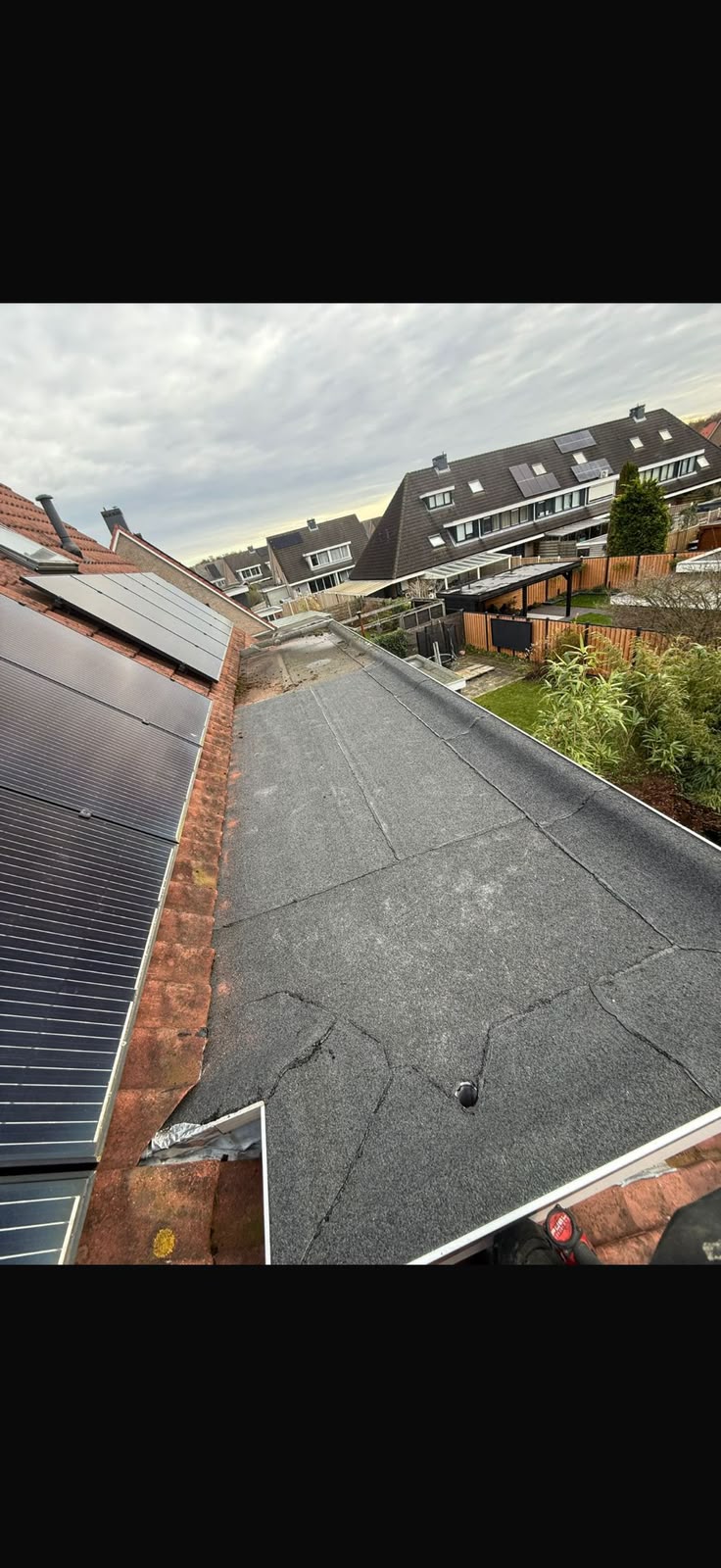 Plat dak met bitumen dakbedekking naast zonnepanelen op een schuin dak