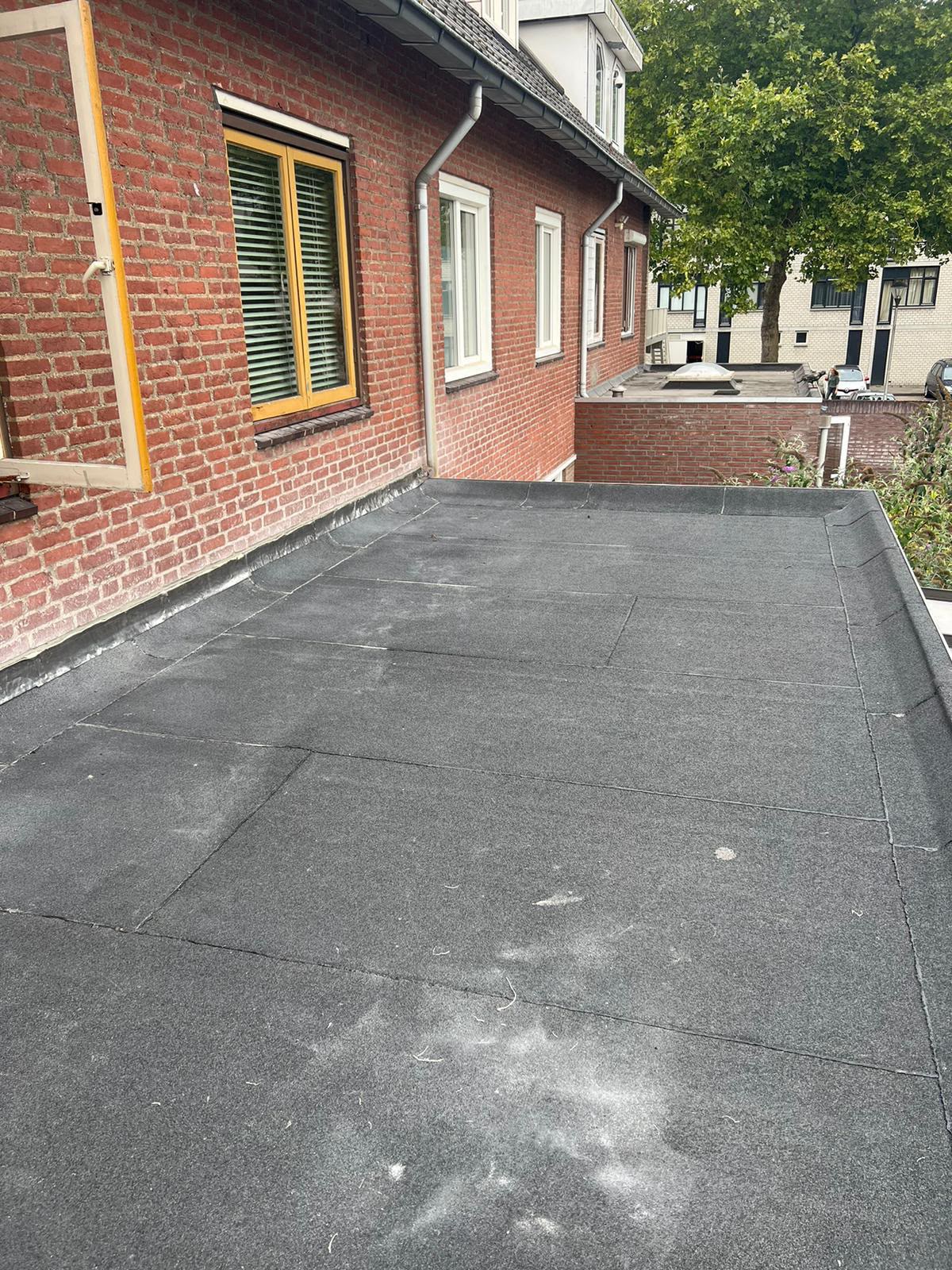 Nieuw aangebracht bitumen plat dak bij een woning met strakke naden en dakopstand